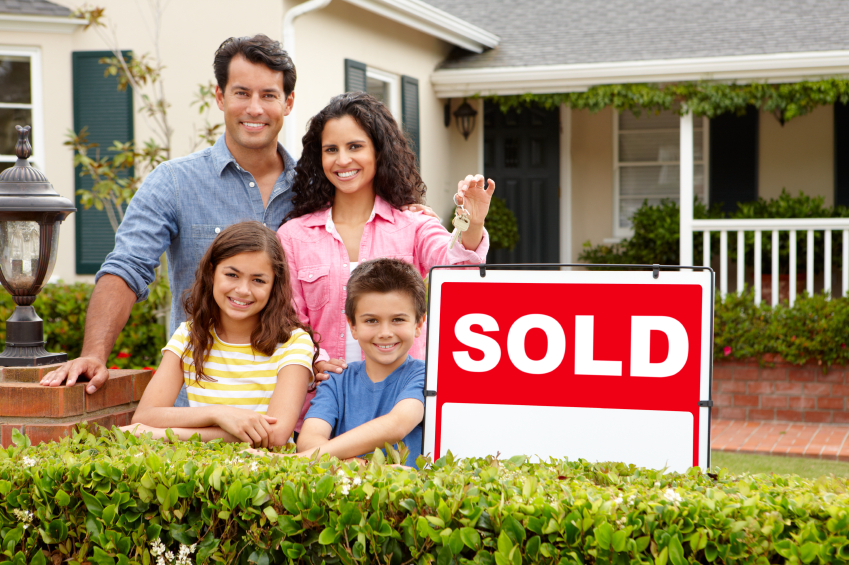 family outside home with sold sign