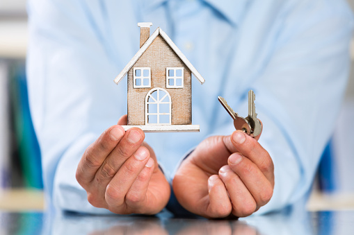 Male Hands holding Miniature House and House Key